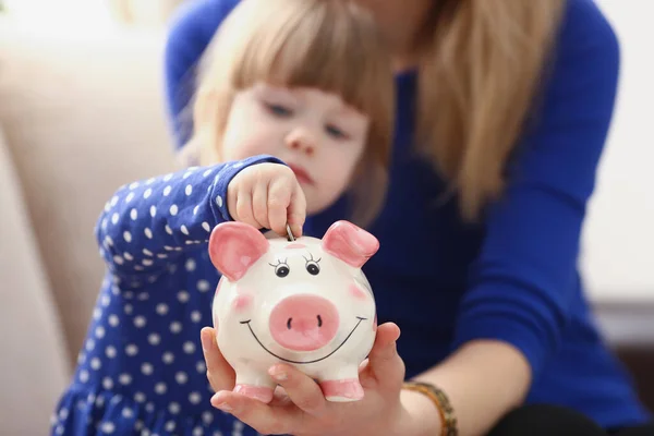 Küçük bir kız pembe domuz kumbarasına bozuk para koyar. — Stok fotoğraf