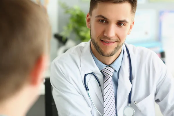 Νεαρός άνδρας γιατρός ακούει έναν ασθενή, κοντινό πρόσωπο — Φωτογραφία Αρχείου