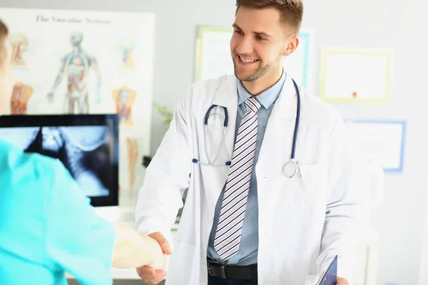 Sonriente médico masculino estrechando la mano con un profesional médico — Foto de Stock
