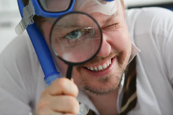 A man looks through a magnifying glass, close-up — Stock Photo, Image