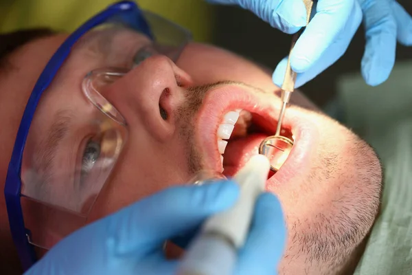 En man behandlar tänder, en patient lugnar ansiktet närbild — Stockfoto