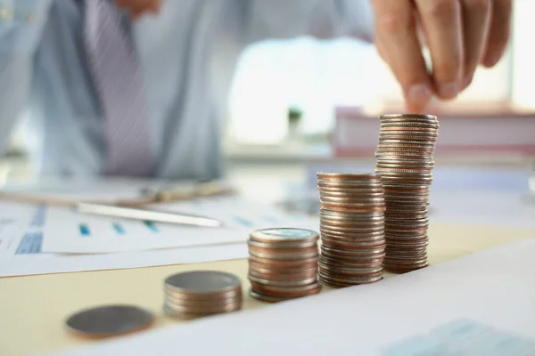 Ein Mann im Büro legt Münzen in eine Reihe, Nahaufnahme — Stockfoto