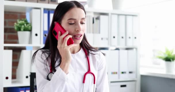 Woman doctor consults patient on phone at workplace — Stock Video