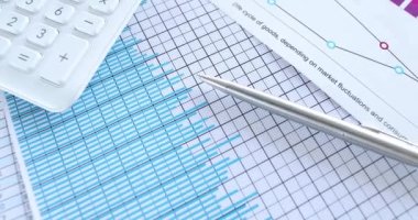 İş çizelgeleri hesap makinesi ve mali belgeler masanın üzerinde.