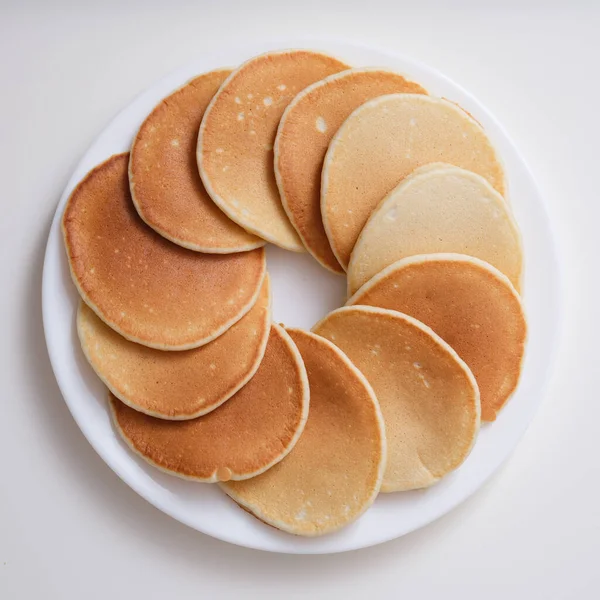Teller mit vielen runden Pfannkuchen auf weißem Hintergrund von oben — Stockfoto