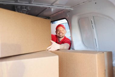 İş yerindeki neşeli adam daha fazla teslimat için kutuları kamyonete koydu.