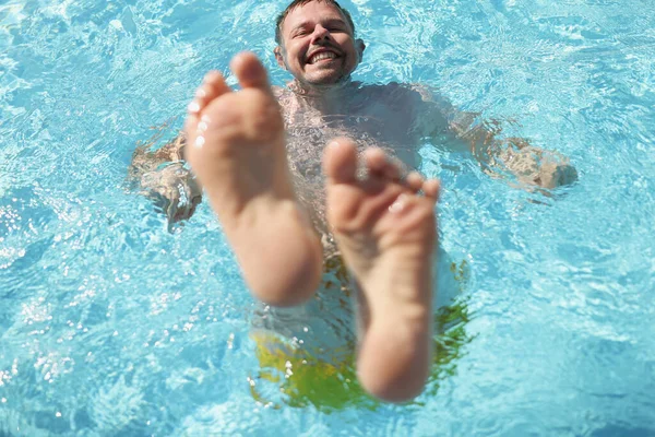 Az ember vízbe merül a medencében, lábakkal felfelé. — Stock Fotó