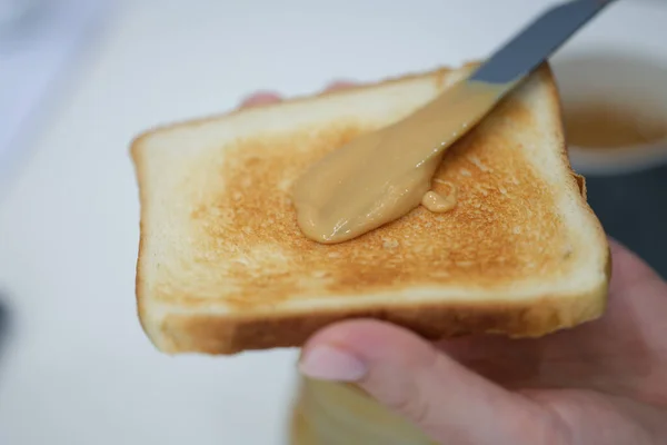 У руках підсмажені тости з арахісовим маслом, розмиті — стокове фото