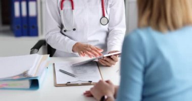 Doktor hastayı dinler ve tablete not alır.