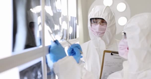 Два лікарі носять захисні медичні костюми та маски, що випромінюють рентгенівські промені — стокове відео