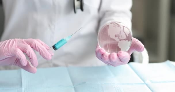 Врач-вирусолог держит стеклянный глобус и шприц с вакциной — стоковое видео