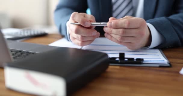 Επιχειρηματίας με επίσημο κοστούμι κρατά στυλό, ενώ κάθεται στο γραφείο — Αρχείο Βίντεο