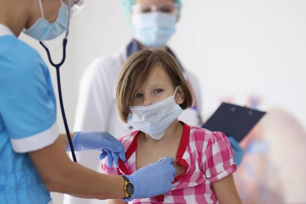 Девочку осматривает врач-педиатр с помощью стетоскопа — стоковое фото