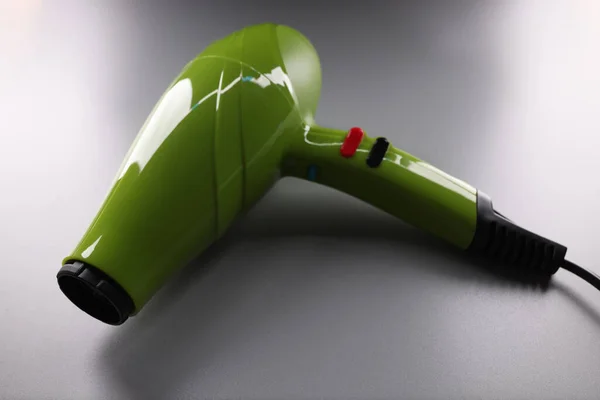 Grön professionell hårtork ligger på grå bakgrund närbild — Stockfoto