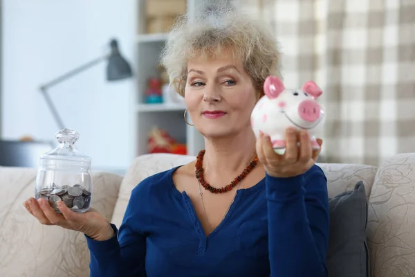 Oudere vrouw op pensioen wegen containers met bespaard geld voor de toekomst — Stockfoto