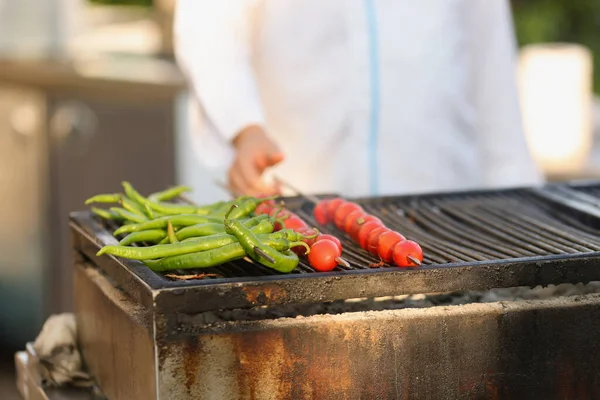 Amatorski kucharz smażący świeże pomidory i zielony pieprz na grillu na świeżym powietrzu — Zdjęcie stockowe