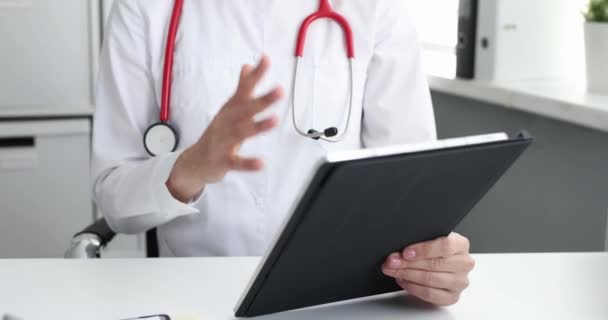 Практикующий врач с помощью планшетного компьютера дает удаленную медицинскую консультацию — стоковое видео