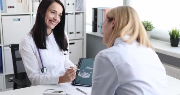 Ginecólogo sonriente y paciente feliz viendo una ecografía del niño en la tableta — Vídeos de Stock