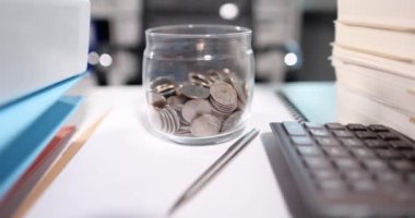 Masaüstü yavaş çekim 4K filminde madeni paralar ve mali belgeler bulunan banka