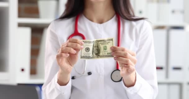 Médico mujer sosteniendo billete de cien dólares cámara lenta película 4k — Vídeos de Stock