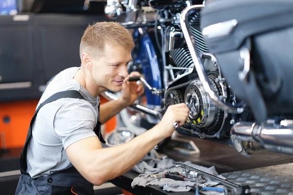 Giovane fabbro smonta motore moto su banco in garage — Foto Stock