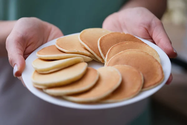 Runde appetitliche Mehlpfannkuchen auf weißem Teller in Frauenhand — Stockfoto