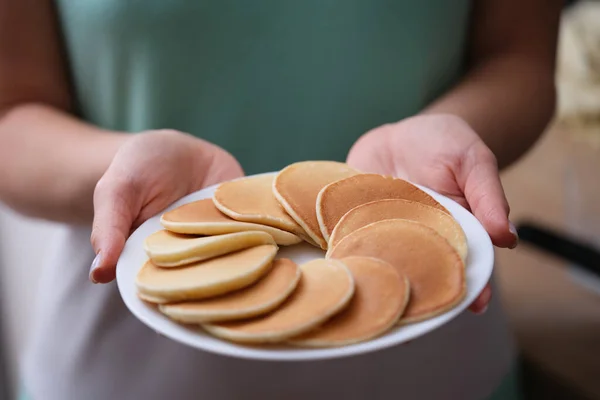 Mehlsüße Pfannkuchen auf weißem Teller in weiblicher Hand Nahaufnahme — Stockfoto