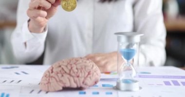 İş kadını Bitcoin parayı beyin modellemesi ve kum saati filminin önünde tutuyor.