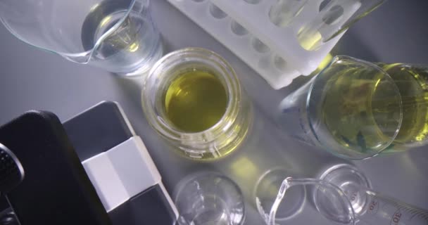 Chemische Reagenzgläser mit Maschinenöl stehen im Labor in der Nähe des Mikroskops Draufsicht 4k Film Zeitlupe — Stockvideo