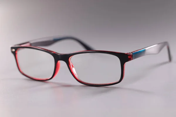 Óculos de plástico na moda vermelho-preto no fundo cinza — Fotografia de Stock