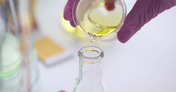 Cientista derrama líquido oleoso amarelo claro em frasco — Vídeo de Stock