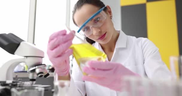 Sarı yağlı sıvı cam matara tutan kadın bilim adamı. — Stok video