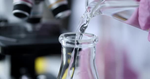 Científico vierte líquido transparente en frasco cámara lenta película 4k — Vídeos de Stock