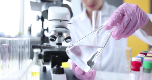 Vetenskapsman håller glaskolv med klar vätska i laboratorium — Stockvideo