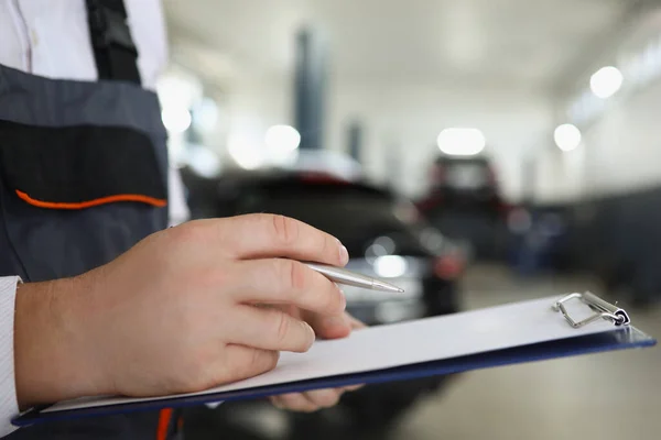 Férfi szolgáltató munkavállaló töltse ki a karbantartási dokumentációt, miután megjavította autó — Stock Fotó