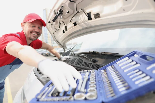 Kraftfahrzeugtechniker lächelt und nimmt Instrument aus offenem Bausatz — Stockfoto