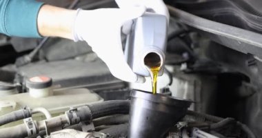 Usta oto tamircisi arabada yağ değiştiriyor.