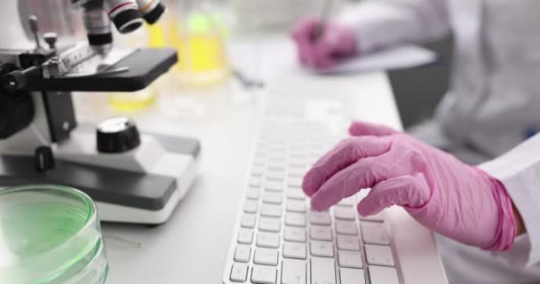 Γιατρός επιστήμονας με γάντια πληκτρολογώντας στο πληκτρολόγιο και γράφοντας λήψη δεδομένων — Αρχείο Βίντεο