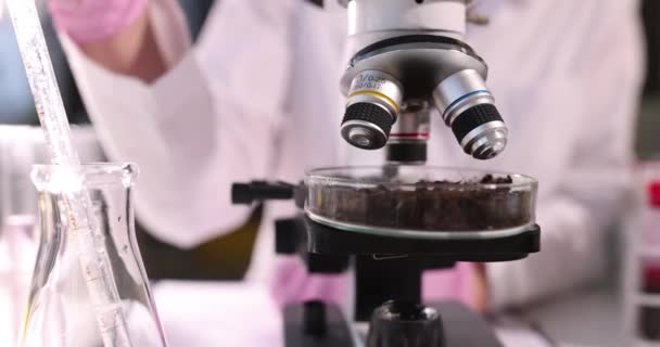Ученый добавил прозрачную жидкость из пипетки в стеклянную тарелку, наполненную почвой — стоковое видео