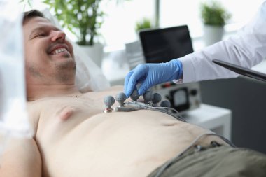 Kardiyolog hastanın göğsüne elektrokardiyogram cihazı yerleştirdi ve kardiyogram testi yaptı.