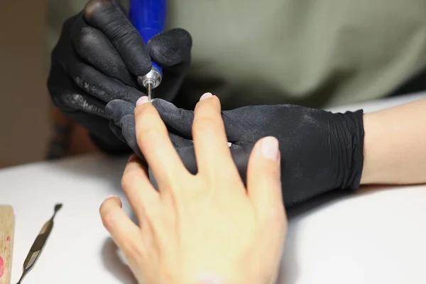 Mistrz paznokci za pomocą sprzętu elektrycznego do czyszczenia paznokci klienta w nowoczesnym studiu kosmetycznym — Zdjęcie stockowe