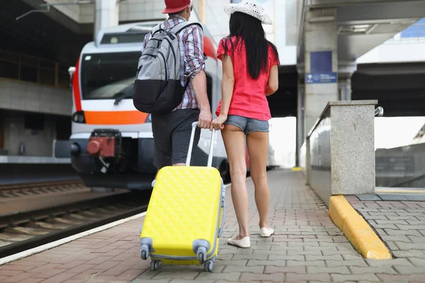 Woman and man with yellow suitcase on train station wait for express train — Stock Photo, Image