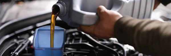 Locksmith mechanic pours engine oil into plastic container on motor engine — Stock Photo, Image