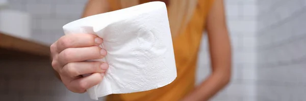 Женщина сидит на унитазе и держит рулон туалетной бумаги — стоковое фото
