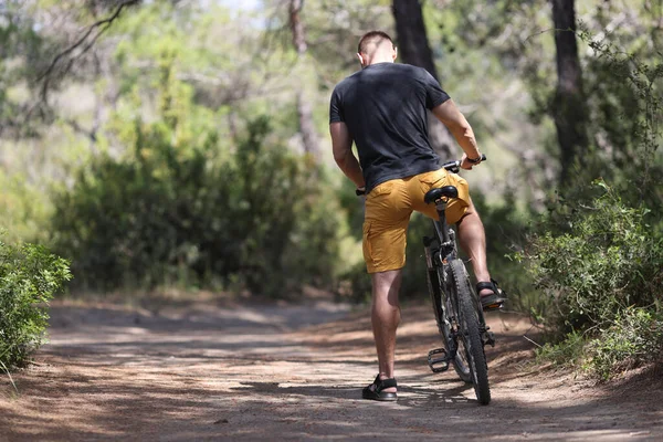 Mann sitzt auf Fahrrad auf Waldweg — Stockfoto