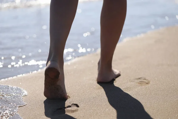 Pies femeninos descalzos caminando a lo largo de la playa del mar primer plano — Foto de Stock