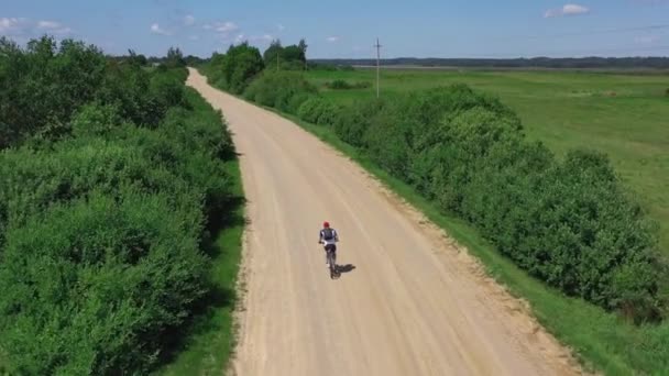 Man op fiets met rugzak fietst langs het veld met bomen bovenaanzicht — Stockvideo