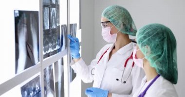 Koruyucu maske takan ve gözlük takan iki doktor röntgen çekiyorlar.