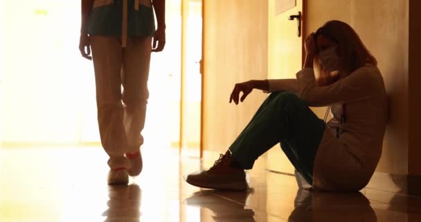 Moe vrouw arts zitten op de vloer in het ziekenhuis gang 4k film slow motion — Stockvideo