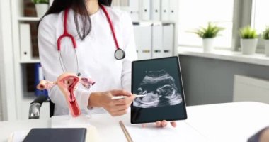 Doktor jinekolog, hamile kadına cenin ultrasonu ile dijital tablet gösteriyor.